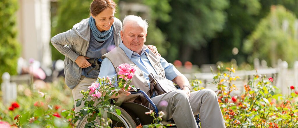 Older couple in garden. Man in wheelchair.