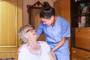Happy Senior woman laughing with her caregiver at home. Senior - Oran Care - Oran Care private home care