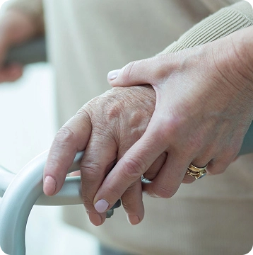 Two hands gripping a walker handle, conveying support for an elderly person with mobility aid